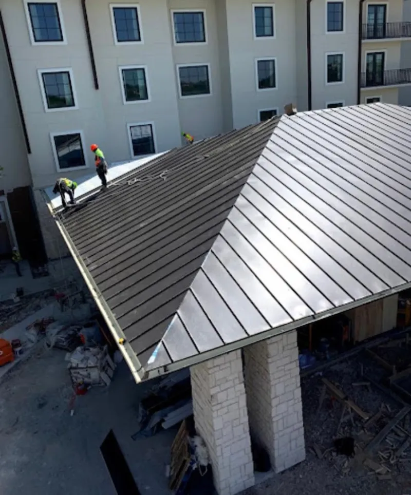 Crew installing standing seam metal roof panels on a commercial project in Salem